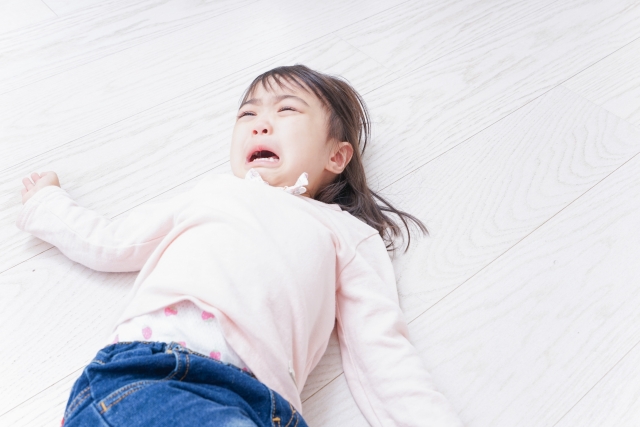 朝に床に寝そべりながら泣く4歳児の女の子の様子